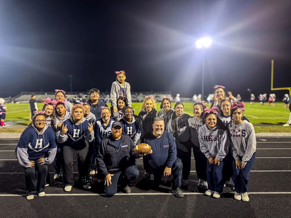 Two EMTs with students at a high school football game